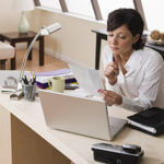 Woman sitting at desk with laptop looking at papers