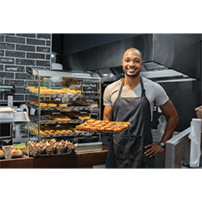 Baker in cafe' holding up full baking sheet