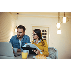 Couple sitting at table looking at laptop