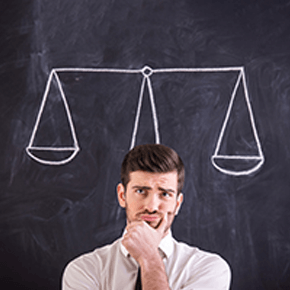 Man in deep thought with a weigh scale chalked on blackboard behind him